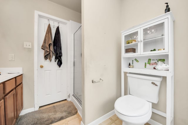 full bathroom featuring a stall shower, vanity, toilet, and baseboards