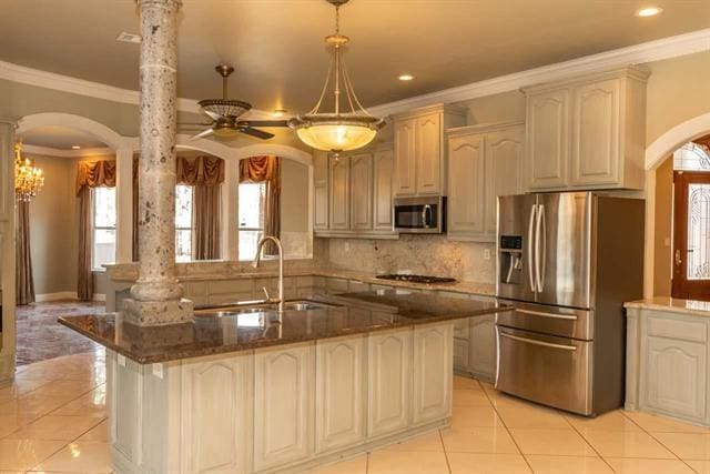 kitchen with dark stone counters, a peninsula, a sink, stainless steel appliances, and backsplash