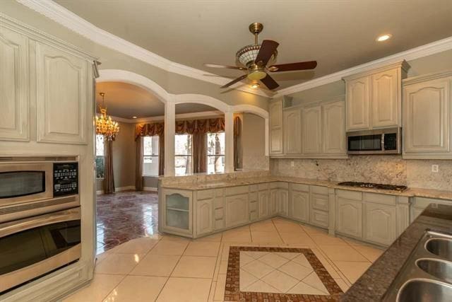 kitchen featuring light tile patterned floors, tasteful backsplash, stainless steel microwave, and gas cooktop