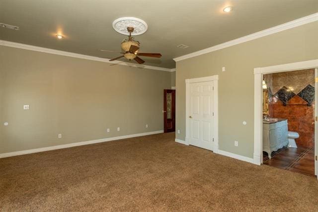 unfurnished bedroom with visible vents, baseboards, dark colored carpet, ensuite bath, and crown molding