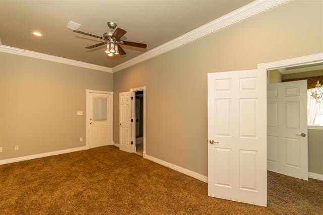 unfurnished bedroom with crown molding, dark carpet, and baseboards