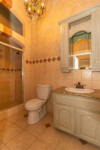 bathroom featuring toilet, tile walls, a shower stall, and vanity