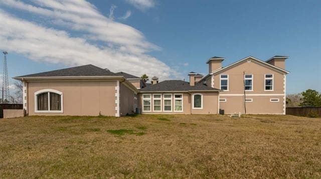 back of property with a lawn and fence