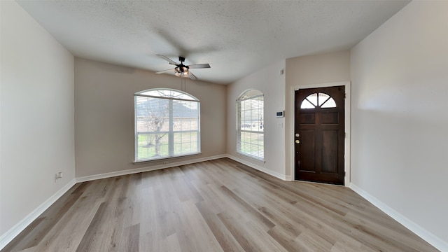 entryway with a textured ceiling, light wood finished floors, a ceiling fan, and baseboards