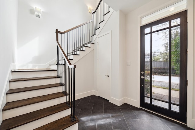 entryway with dark tile patterned floors, stairway, and baseboards