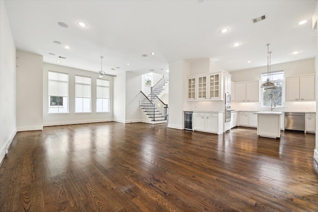 unfurnished living room with wine cooler, recessed lighting, dark wood-style flooring, visible vents, and stairs