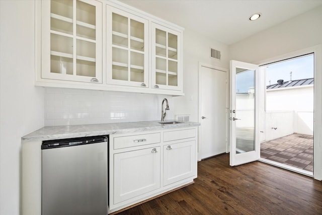 kitchen featuring visible vents, glass insert cabinets, light stone counters, white cabinetry, and backsplash