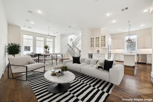 living room with stairs, visible vents, dark wood-type flooring, and recessed lighting