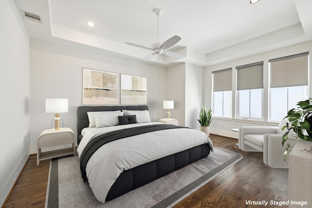 bedroom featuring dark wood-style floors, a raised ceiling, and baseboards