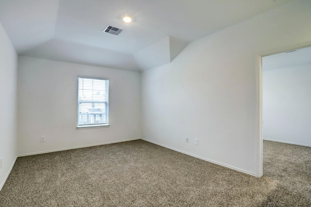 spare room with carpet floors, baseboards, visible vents, and lofted ceiling