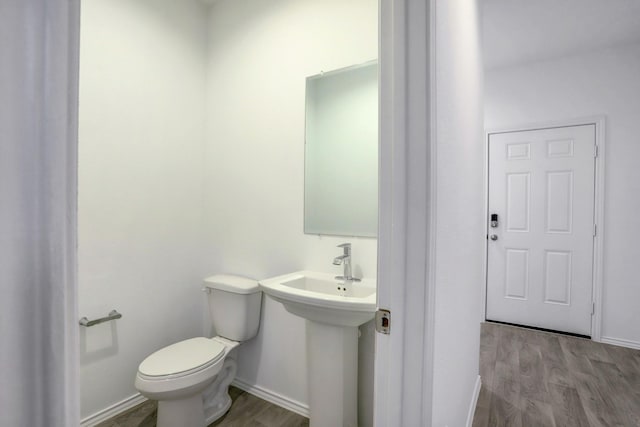 bathroom with baseboards, a sink, toilet, and wood finished floors