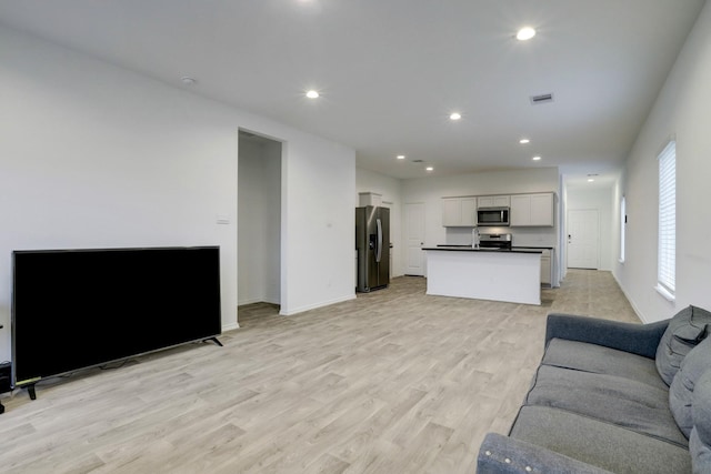 living room featuring baseboards, recessed lighting, visible vents, and light wood-style floors