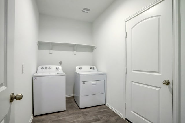 washroom with laundry area, washing machine and dryer, baseboards, and wood finished floors