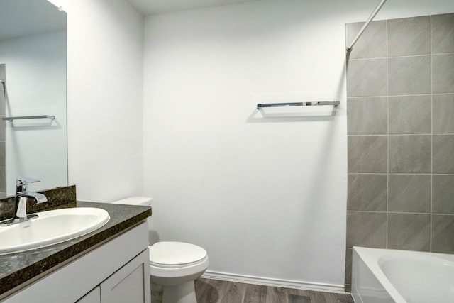 full bathroom with toilet, wood finished floors, vanity, baseboards, and washtub / shower combination