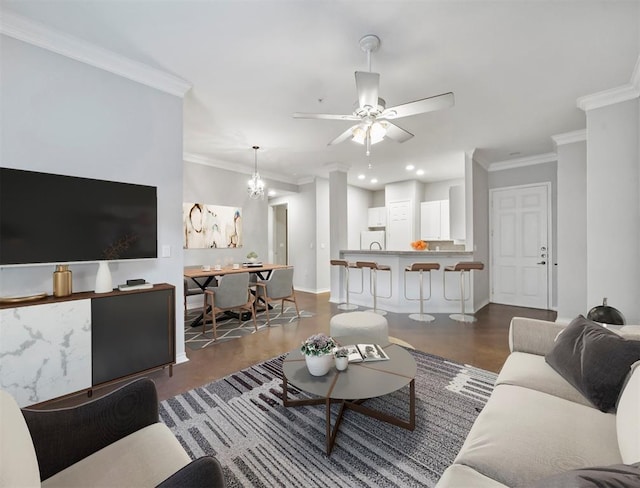 living room featuring recessed lighting, baseboards, crown molding, and ceiling fan with notable chandelier