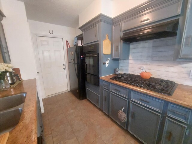 kitchen with black appliances, gray cabinetry, range hood, and a sink