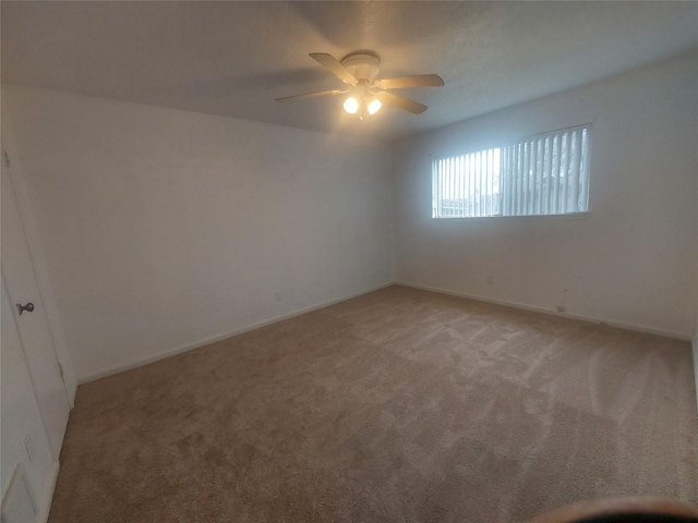 empty room with baseboards, light carpet, and a ceiling fan