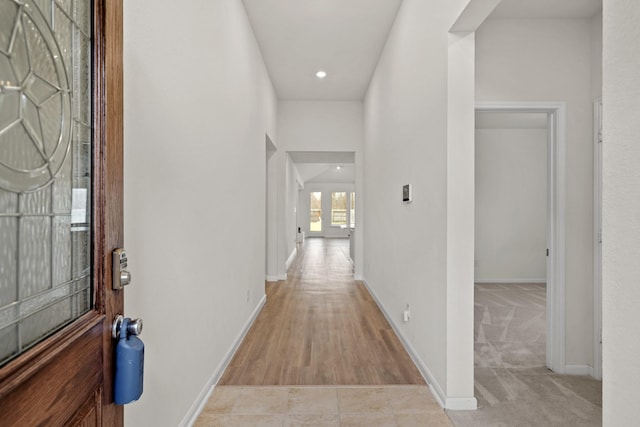 hall with recessed lighting, light colored carpet, and baseboards