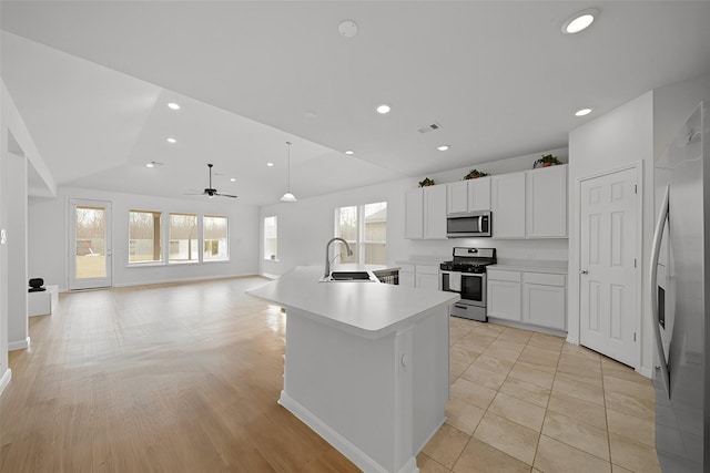 kitchen with a sink, white cabinetry, light countertops, appliances with stainless steel finishes, and a center island with sink