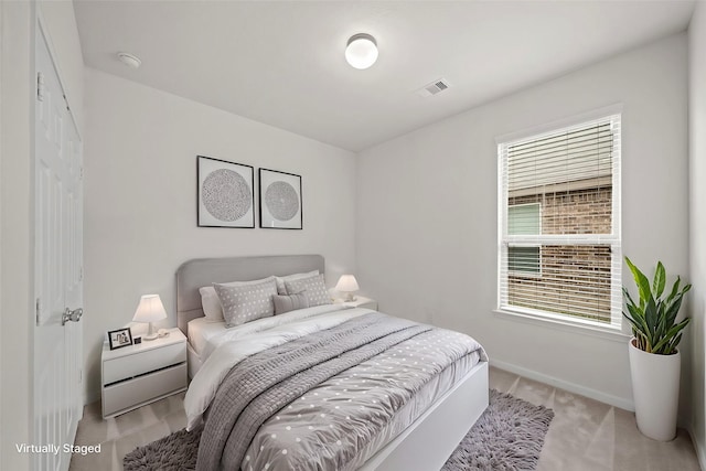 bedroom with baseboards, visible vents, and light colored carpet