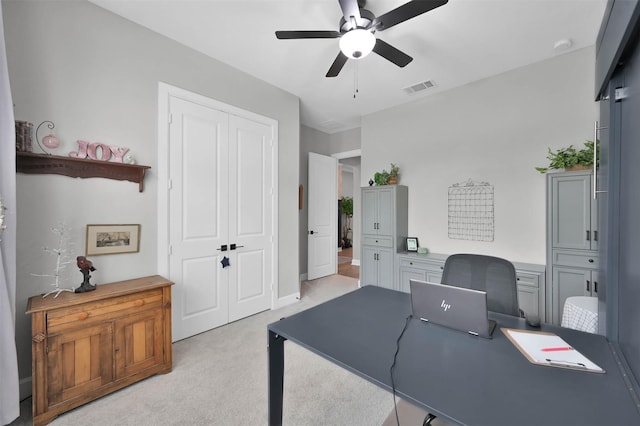 office space featuring light carpet, visible vents, and a ceiling fan