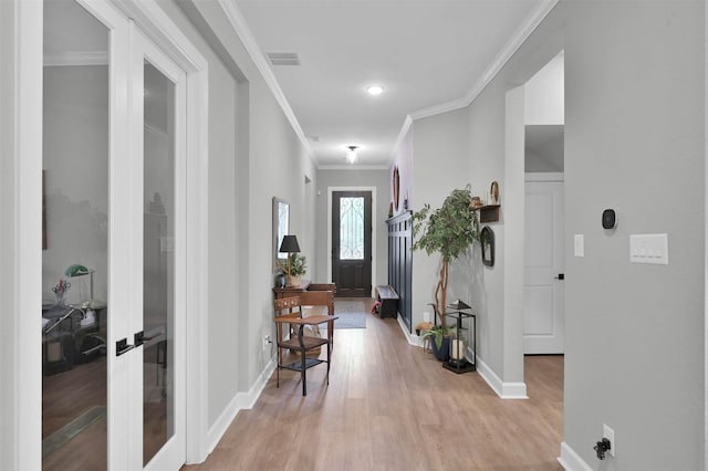 foyer entrance featuring crown molding, light wood finished floors, visible vents, and baseboards