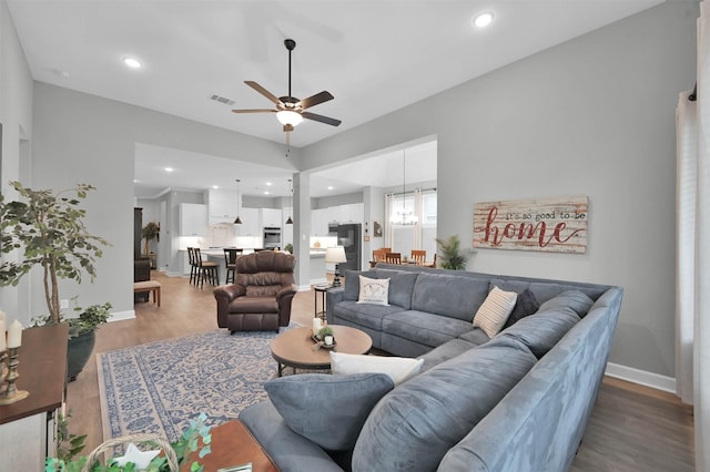 living room with recessed lighting, visible vents, wood finished floors, baseboards, and ceiling fan with notable chandelier