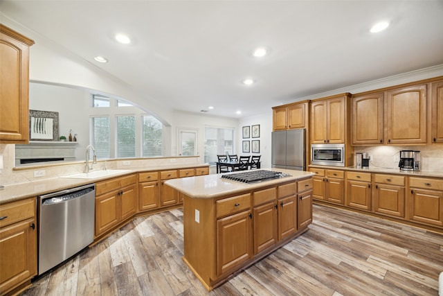 kitchen with tasteful backsplash, a kitchen island, light countertops, stainless steel appliances, and a sink