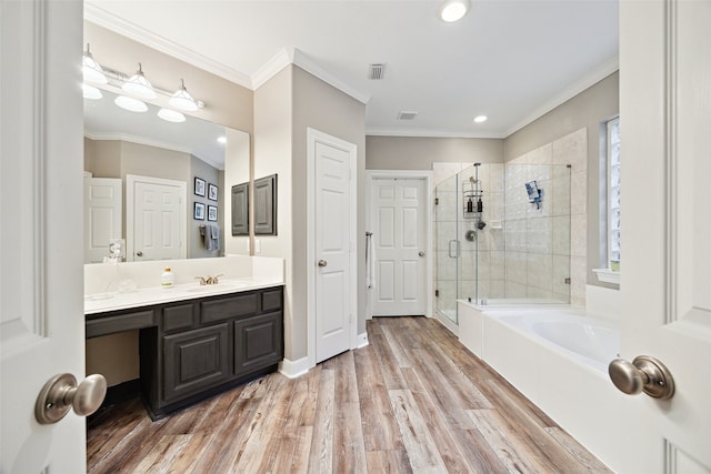 bathroom featuring a shower stall, crown molding, wood finished floors, a bath, and vanity