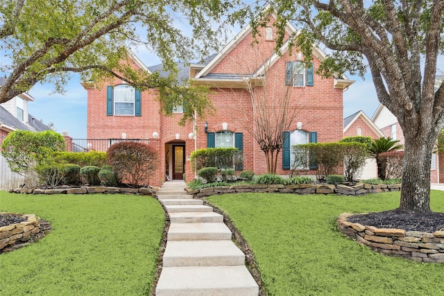 view of front facade with brick siding and a front yard