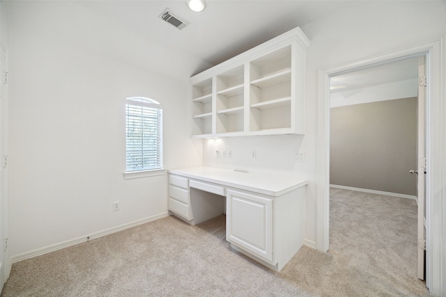 unfurnished office with visible vents, baseboards, light colored carpet, and built in desk