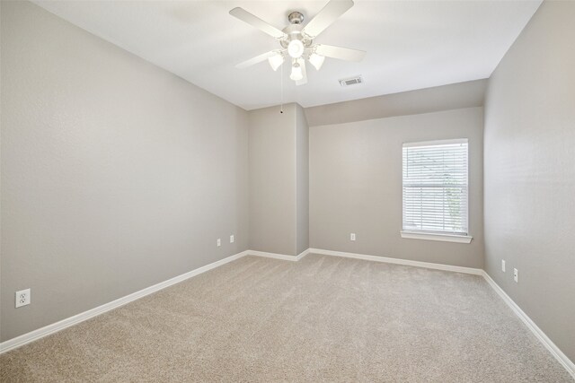 spare room featuring light colored carpet, a ceiling fan, visible vents, and baseboards