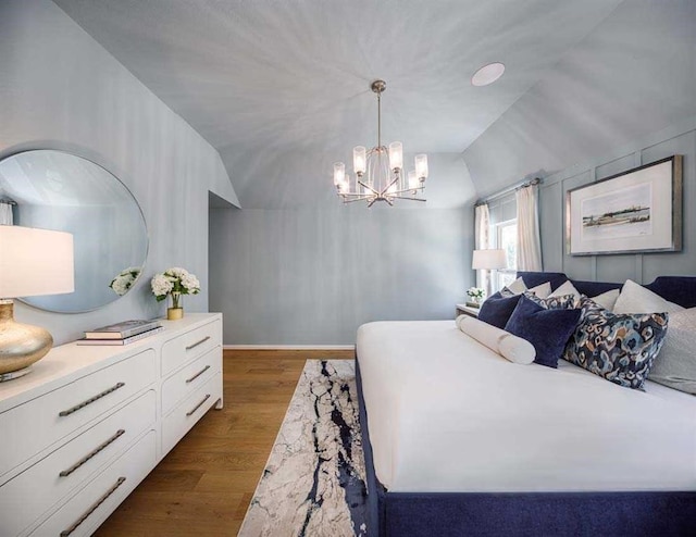 bedroom with dark wood-type flooring, vaulted ceiling, baseboards, and an inviting chandelier