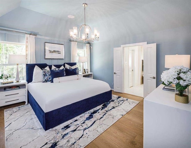 bedroom with a chandelier, multiple windows, vaulted ceiling, and light wood-style flooring