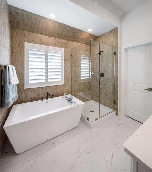 full bath featuring marble finish floor, recessed lighting, a soaking tub, and a stall shower