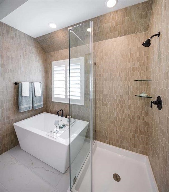 full bath featuring a stall shower, lofted ceiling, a soaking tub, tile walls, and recessed lighting