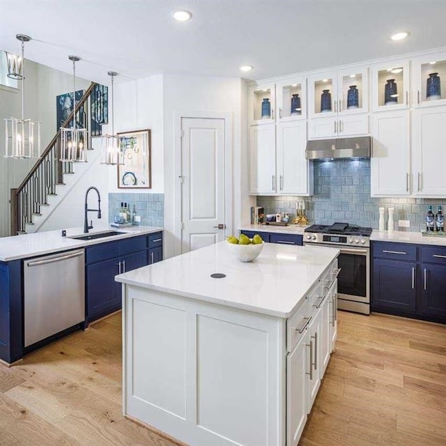 kitchen featuring under cabinet range hood, white cabinetry, appliances with stainless steel finishes, and a center island