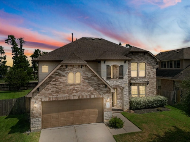 french country inspired facade featuring a garage, brick siding, driveway, and fence