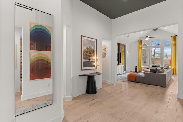 corridor with light wood-style floors, baseboards, high vaulted ceiling, and beamed ceiling