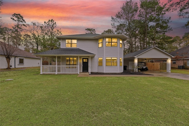 view of front of home with a yard, a porch, concrete driveway, central AC, and a carport