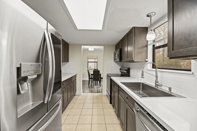 kitchen with stainless steel appliances, light countertops, a sink, and hanging light fixtures