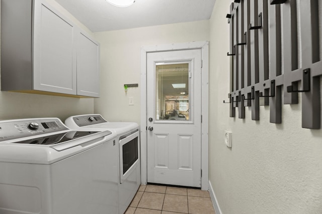 laundry area with light tile patterned floors, washing machine and clothes dryer, cabinet space, and baseboards