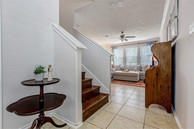 foyer with light tile patterned floors, ceiling fan, a textured ceiling, baseboards, and stairs