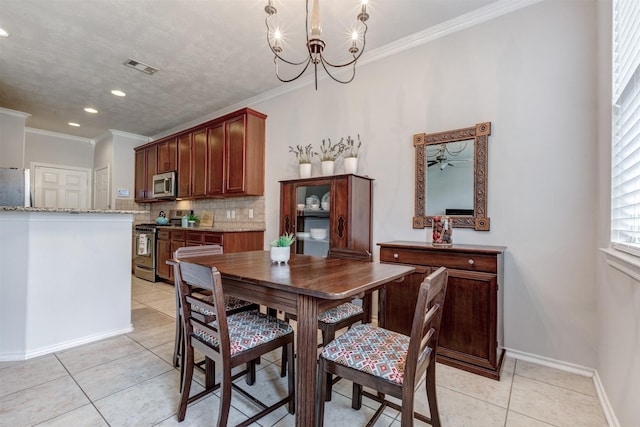 dining room with light tile patterned floors, baseboards, visible vents, ornamental molding, and a notable chandelier