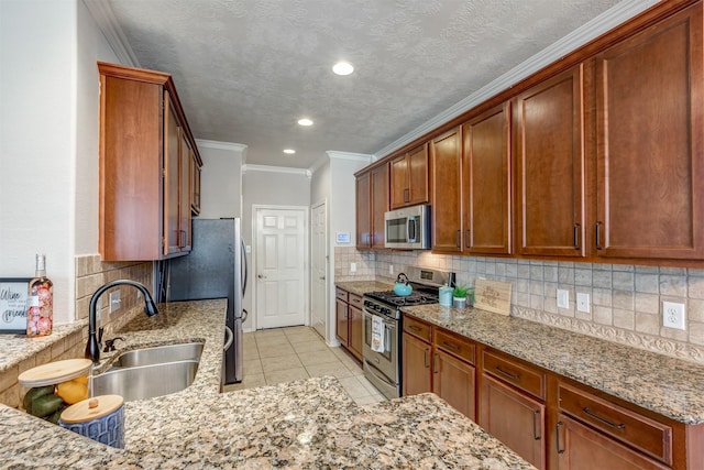 kitchen with light stone countertops, appliances with stainless steel finishes, decorative backsplash, and a sink