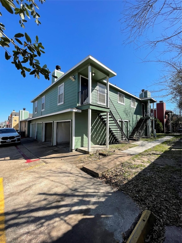 view of front of home with a chimney, stairway, and concrete driveway