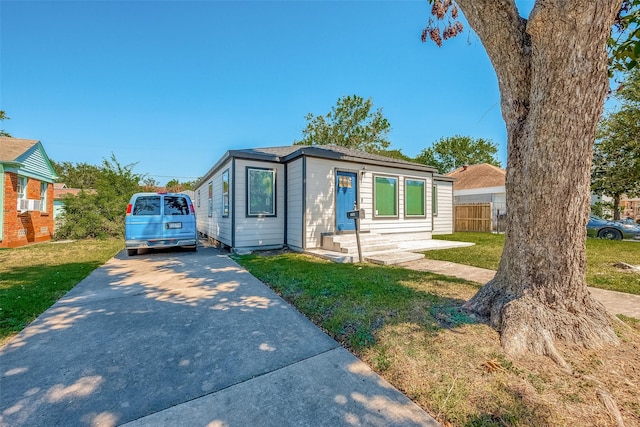 view of front of house featuring driveway, a front lawn, and fence