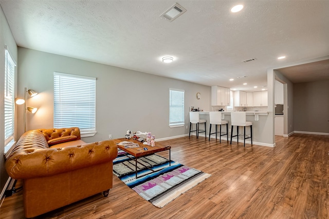 living room with light wood finished floors, visible vents, and baseboards