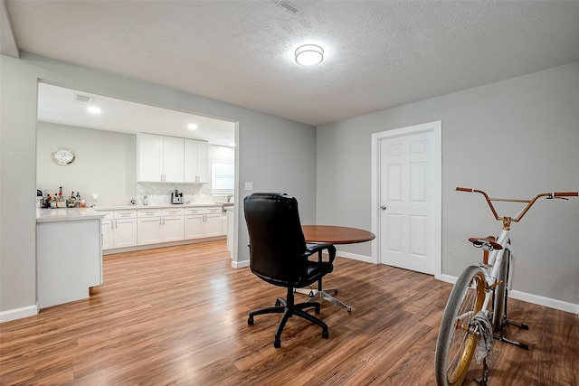 home office with baseboards, visible vents, and light wood finished floors