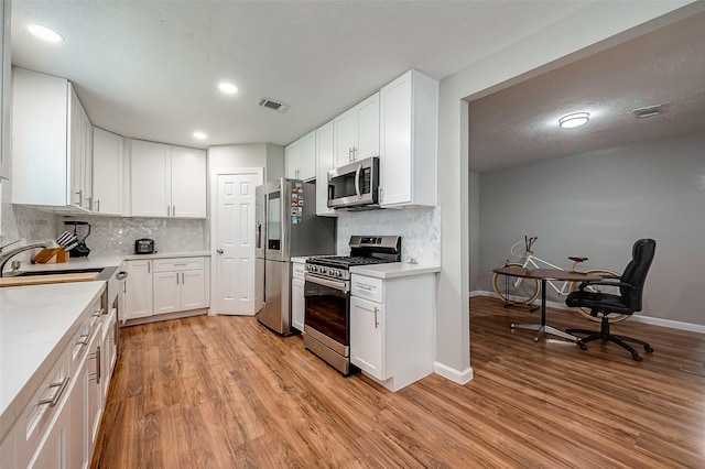 kitchen with a sink, visible vents, white cabinets, light countertops, and appliances with stainless steel finishes